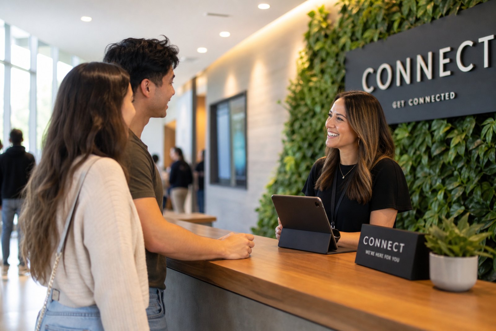 A volunteer welcoming a young couple at the connect desk